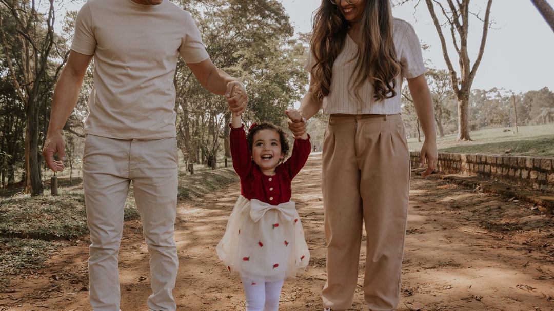 Criança de mãos dadas com o pai e a mãe